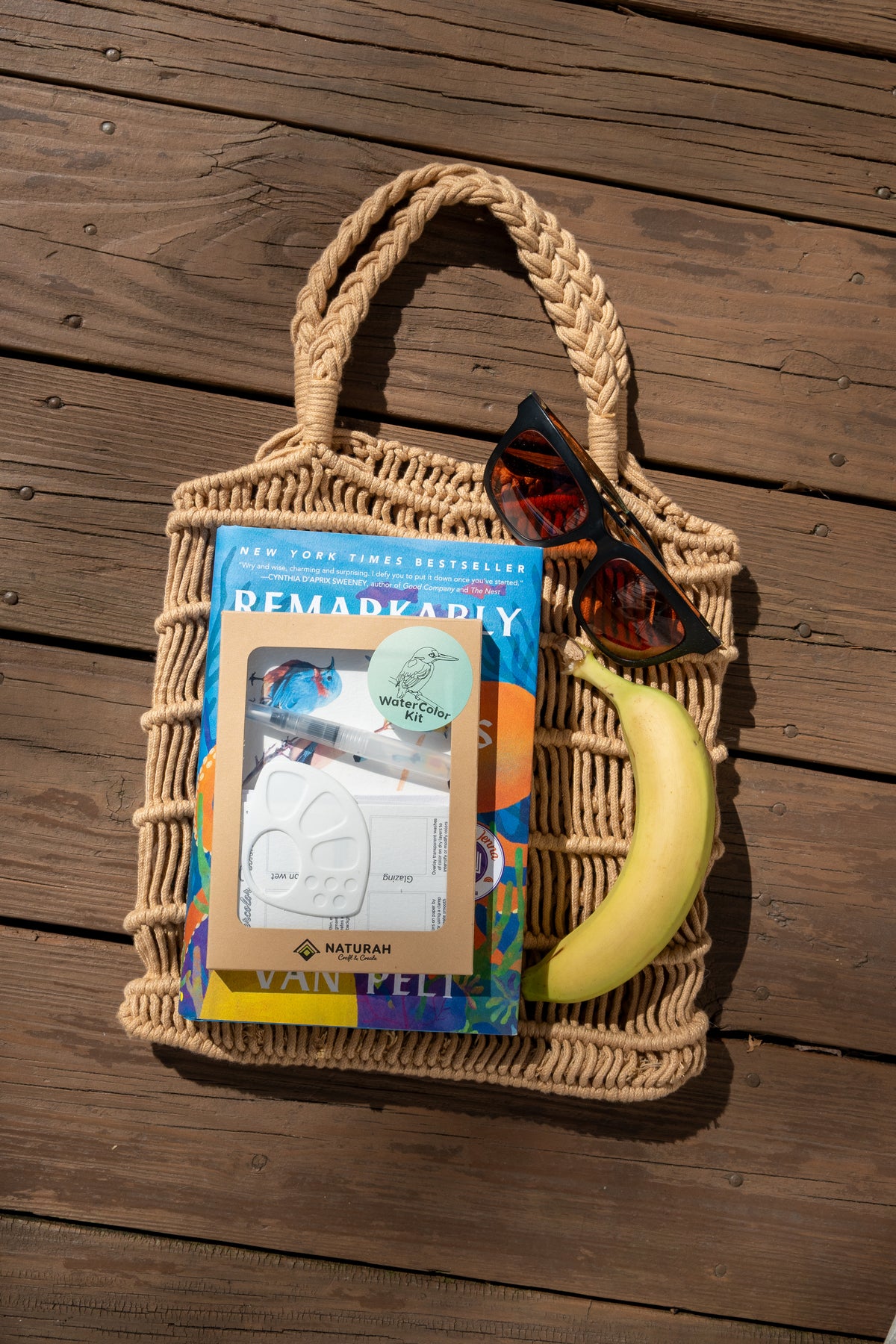 The Naturah Birds Watercolor Set tucked into a macramé tote with a book and sunglasses on a sunlit deck — ready to take anywhere.